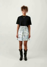 Black short-sleeve t-shirt paired with light blue patterned shorts featuring floral and wave designs; knee-high black boots.