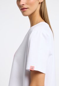 Witte katoen T-shirt met korte mouwen, voorzien van een roze accentlabel op de linkermouw. Eenvoudig ontwerp met een relaxte pasvorm.
