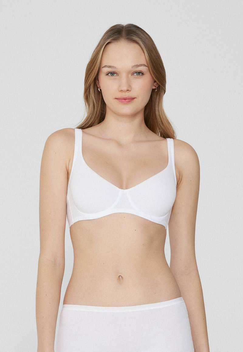 Witte stoffen beha met een gladde textuur, ondertsteuning door beugels en brede bandjes. Heeft een klassiek ontwerp zonder extra patronen of details.