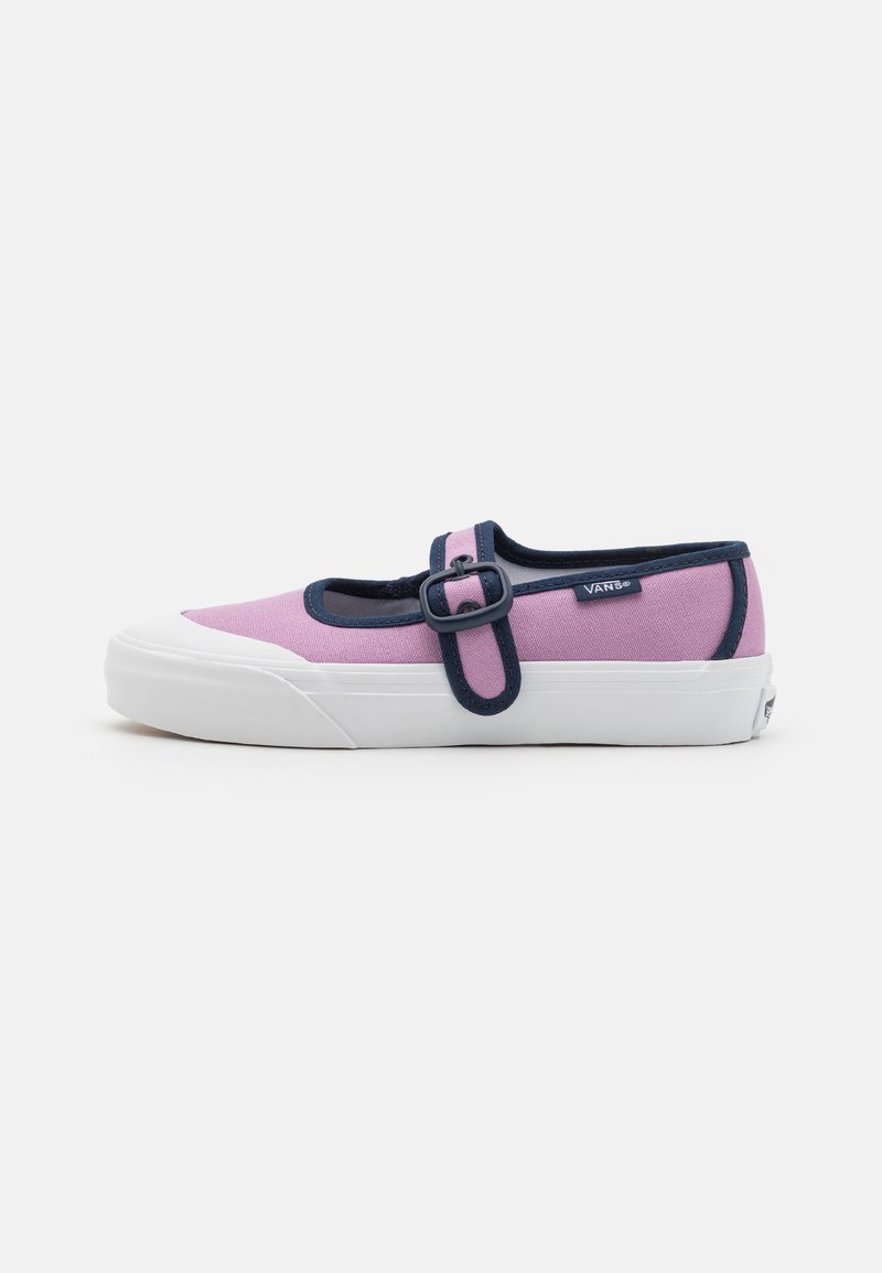 Pink canvas shoe with a navy strap and buckle, white rubber sole, rounded toe, and a textured upper. Logo tag on the side.