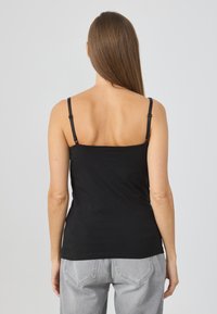 Μαύρο αμάνικο τοπ με ρυθμιζόμενους ιμάντες, εφαρμοστή γραμμή και απαλή υφή. Διαθέτει απλό σχέδιο χωρίς μοτίβα ή διακοσμητικά.