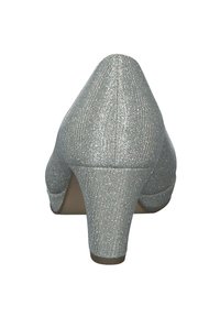 Scarpa con tacco alto argento glitterato, con punta affusolata, tessuto texturizzato e tacco discreto. La parte posteriore presenta un design arrotondato e liscio.