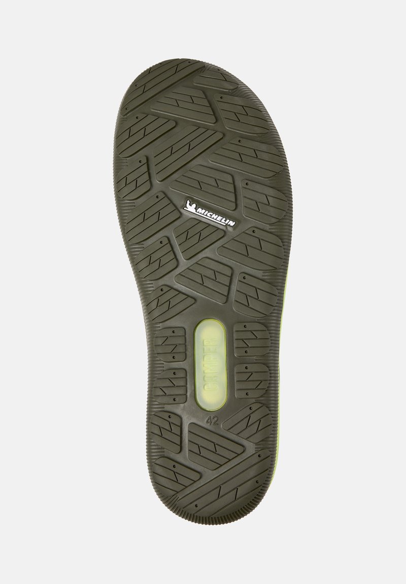 Sål af en sko med et tekstureret slidbane-mønster, mærket med "Michelin" og "Camper," størrelse markeret som 42. Klart grønt detaljer synlige.