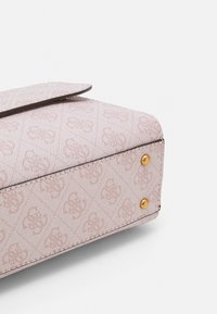 Vaaleanpunainen teksturoitu laukku, jossa on kohokuvioitu kuvio, kultaiset yksityiskohdat, läppäkiinnitys ja kontrastivärinen musta reunapisto.