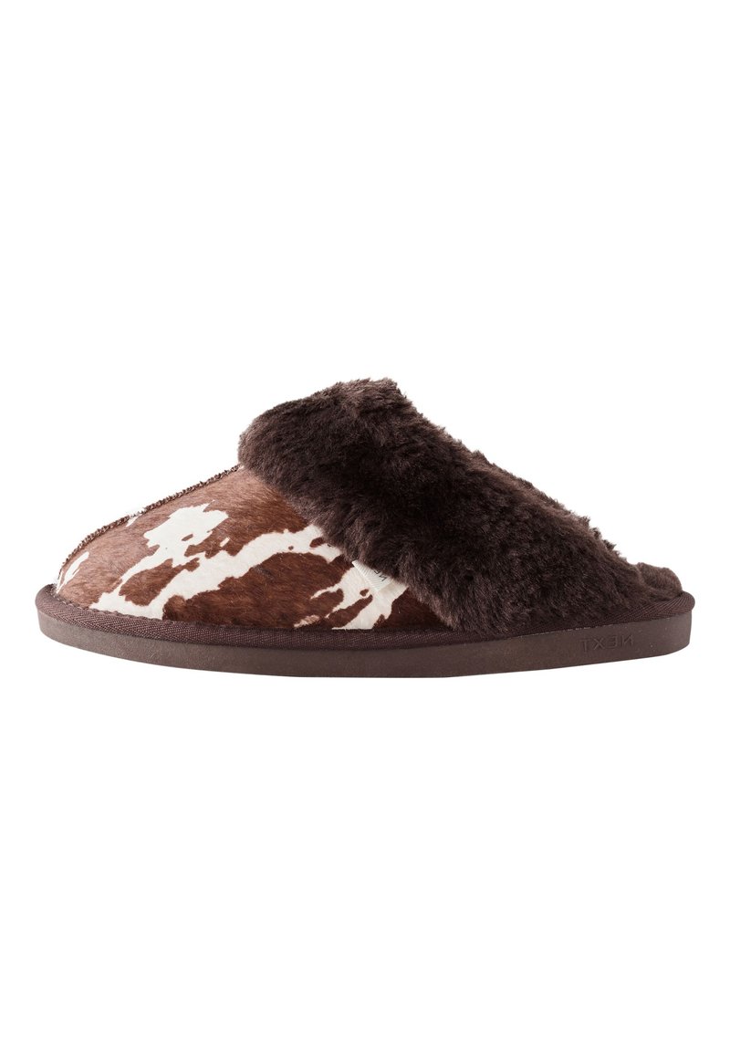 Kapcie w brązowo-biały wzór w cętki jak u krowy, z puszystym ciemnobrązowym paskiem, gładką fakturą i zaokrąglonym kształtem, wyposażone w gumową podeszwę.