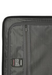 Black travel case interior featuring a zippered mesh pocket, a solid zipped compartment, and subtle vertical stripe patterns on a textured fabric.