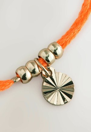 Bracciale in corda arancione intrecciata con perline d'argento e un pendente rotondo che presenta un motivo a raggi di sole. Il pendente ha una finitura lucida.