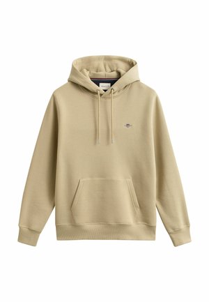 Sweat à capuche beige avec poche kangourou à l'avant, capuche à cordon de serrage, poignets côtelés et petit blason brodé sur la poitrine gauche.