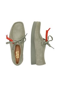 Chaussures en daim vert clair avec un bout arrondi, une languette à l'arrière et un accent de lacet rouge contrastant ; semelle en caoutchouc avec un motif texturé.