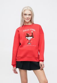 Κόκκινο φούτερ με γραφικό σχέδιο μιας όμορφης ελαφίνας και λουλουδιών; διαθέτει ριμπ μανσέτες και στρίφωμα, άνετη εφαρμογή και μαλακή υφή. Συνοδεύεται από μια μαύρη φούστα.