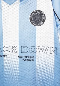 Light blue and white striped sports jersey with black text saying "KEEP PUSHING FORWARD" and a circular patch reading "LEAVE IT ALL BEHIND NO BACK DOWN."