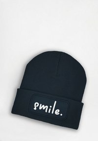 Navy knit beanie with a ribbed texture and a rectangular patch displaying the word "smile." in white lettering.