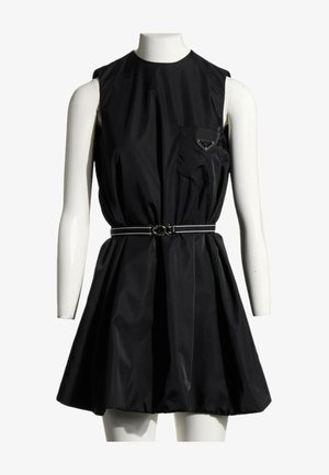 Robe mini noire sans manches avec une ceinture ajustée à la taille, une poche sur la poitrine à l'avant et une jupe évasée, présentée sur un mannequin blanc.