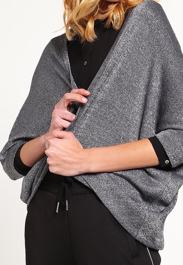 Metalický šedý šál s volným střihem, měkkou texturou a širokými rukávy, nošený přes černou košili a doplněný černými tepláky.