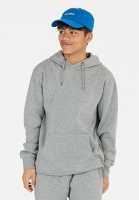 Grijze hoodie met een kangoeroezak, voorzien van een capuchon en trekkoorden. Gecombineerd met bijpassende grijze sweatpants. Blauwe pet met geborduurde tekst.