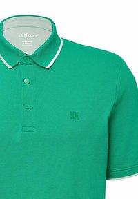 Grünes Poloshirt aus strukturiertem Stoff mit klassischem Kragen, drei Knöpfen und weißen Akzenten entlang des Kragens und der Ärmel. Verfügt über ein Logo.