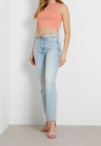 Hellrosa kurzes Tanktop, hochtaillierte hellblaue Jeans und hellrosa Sandalen. Glatte Textur und figurbetontes Design.