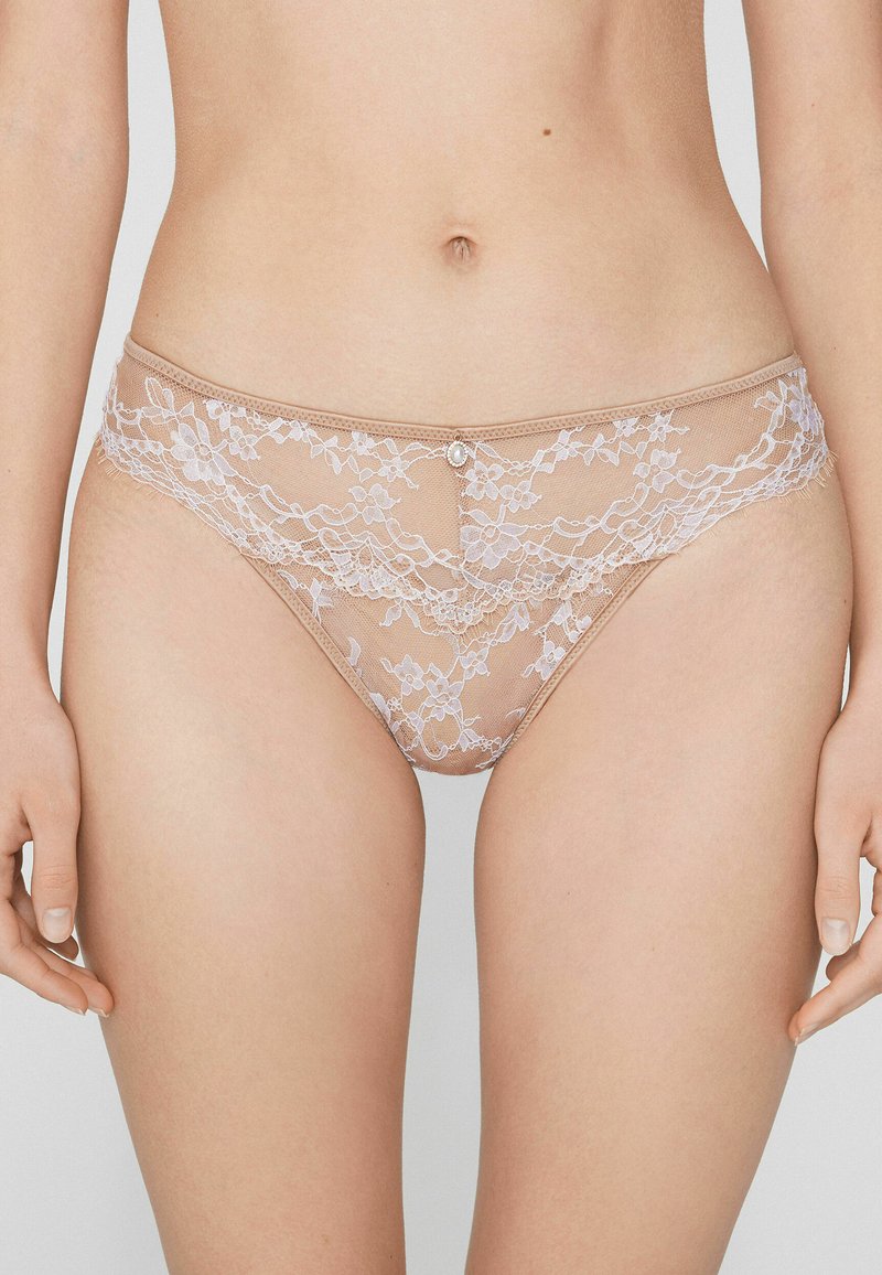 Lace thong featuring a nude sheer material with floral patterns, a decorative pearl accent at the front, and a soft, smooth texture.