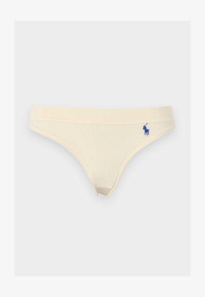 Γυναικεία μπικίνι σε κρεμ χρώμα με μικρό μπλε κεντημένο λογότυπο στο αριστερό ισχίο, σε λευκό φόντο.