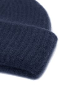 Bonnet tricoté en laine douce de couleur bleu marine foncé, avec une texture côtelée et un revers replié pour plus de chaleur.