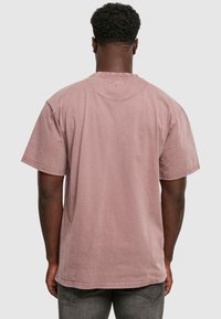 Lühikeste varrukatega, vabalt istuv T-särk tuharoosas, pehmest kangast, ümmarguse kaelusega ja selja õmblustega.