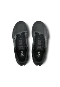 Baskets de sport noires avec une tige en mesh, présentant un design texturé, des lacets noirs et des détails de logo. Légères avec une semelle rembourrée.