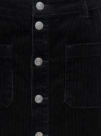 Zwarte corduroy stof met verticale ribbels, voorzien van vijf zilverkleurige metalen drukknopen en twee rechthoekige opgestikte zakken.