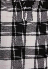 Tessuto a quadri bianco e nero con una delicata linea rosa, che mette in mostra una texture tessuta e strisce di spessore contrastante.