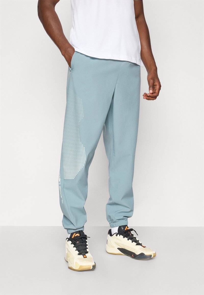 Lys blå joggere med et strukturert design, elastiske mansjetter og sidelommer, kombinert med beige og svarte joggesko.