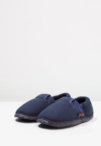 Marineblauwe stoffen slippers met een gestructureerde zwarte zool en elastische accenten voor een betere pasvorm. Rond afgewerkte neus, zachte voering en minimale branding.