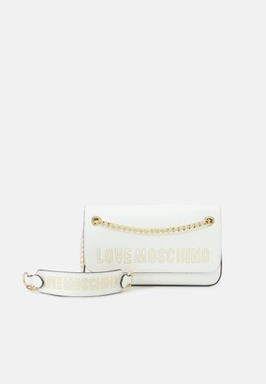 Valkoinen Love Moschino -laukku, jossa on kullanvärinen ketjuhihna ja irrotettava valkoinen olkahihna, etupuolella kultaisia niittejä sisältävä brändilogot.