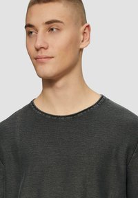 Zwarte gemêleerde sweatshirt met een ronde halslijn en zichtbare stikseldetails, met een losse pasvorm en zachte stof.