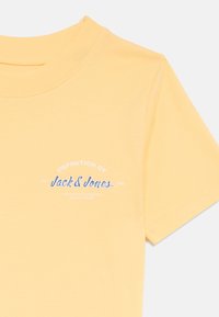 Κίτρινο βαμβακερό t-shirt με κοντά μανίκια, που διαθέτει μπλε και λευκό σχεδιασμό με γραφικό κείμενο που γράφει «ΟΡΙΣΜΟΣ ΤΟΥ Jack & Jones.»