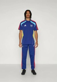 Blue sports tracksuit with multicolor accents, featuring red and turquoise stripes, white Adidas logo, and an emblem on the chest.