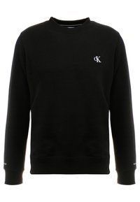 Sweat-shirt noir à manches longues avec col rond, petit logo CK blanc sur le côté gauche de la poitrine et texte discret près des poignets.