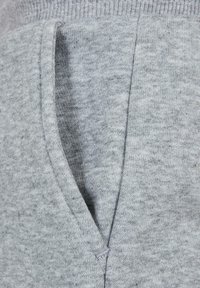 Primer plano de un bolsillo de tela gris en una prenda de punto que muestra la textura y los detalles de la costura.