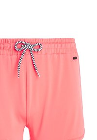 Bañadores de hombre en tejido rosa brillante, con cinturilla elástica y cordón en chevron en blanco y negro, textura suave.