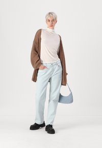 Knitattu ruskea neuletakki, vaalea beige poolopaita, vaaleansiniset suorat farkut, mustat korokepohjat ja pieni sininen käsilaukku.