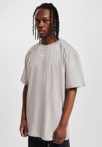 Light grey short-sleeve t-shirt, featuring a round neckline and discreet embroidered logo on the chest. Smooth cotton texture.