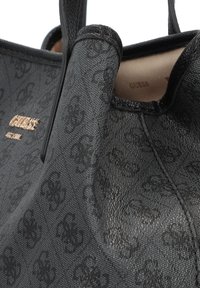 Sac fourre-tout noir en tissu texturé, avec un motif logo subtil, des accents lisses et un logo de marque doré. Doté de poignées robustes.