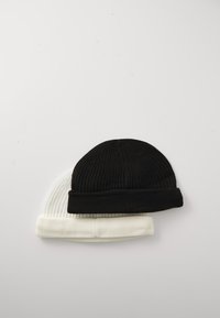 To strikkede huer stablet ovenpå hinanden; en sort, en hvid. Ribbet tekstur, foldbart opsmøg på hver, rund topform. Minimalistisk design.