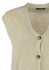 Gilet tricoté couleur crème avec motif losanges, col en V et deux boutons marron sur le devant.