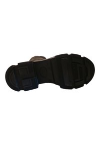 Suela de goma negra con superficie texturizada, que presenta una puntera reforzada y un patrón de relieve distintivo para mayor agarre. Correas ajustables para un mejor ajuste.
