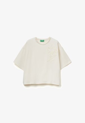 Haut court à manches courtes de couleur blanc cassé avec col rond et broderie florale en relief sur le côté gauche de la poitrine, étiquette indiquant United Colors of Benetton.