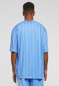 Tricou sport cu dungi albastre, cu mâneci scurte, fabricat dintr-un material respirabil. Prezintă un guler nervurat și un logo brodat pe mâneca stângă.