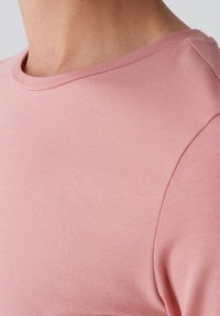 Růžové tričko z bavlny s kulatým výstřihem a hladkou strukturou. Krátké rukávy a jednoduchý design s jemným švem na rameni.