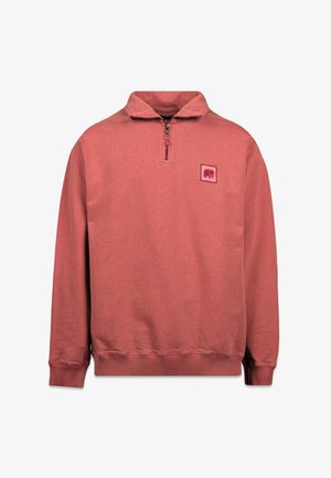 Roter Pullover mit hohem Kragen, halbem Reißverschluss und einem quadratischen Logo-Patch auf der linken Brust. Gerippte Bündchen und Saum sorgen für Textur.
