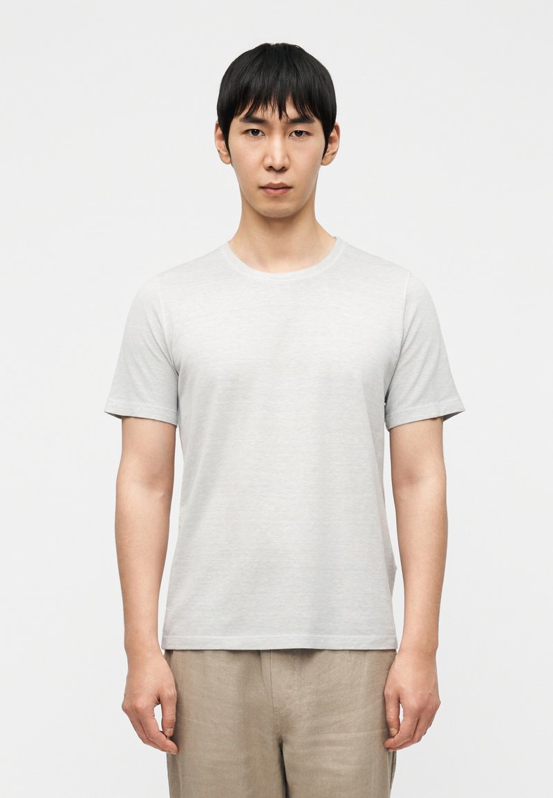 Ελαφρώς γκρι μπλουζάκι με στρογγυλή λαιμόκοψη από μαλακό ύφασμα, με κοντά μανίκια και άνετη εφαρμογή. Απλός, χωρίς διακοσμητικά σχέδιο.