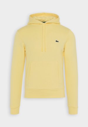Lichtgele capuchonsweater met zak aan de voorkant, trekkoorden en een klein groen krokodillenlogo op de linkerborst.