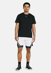 Sort T-shirt med korte ærmer og hvide netshorts med sorte kanter. Sneakers med et struktureret design. Enkel, sporty stil.